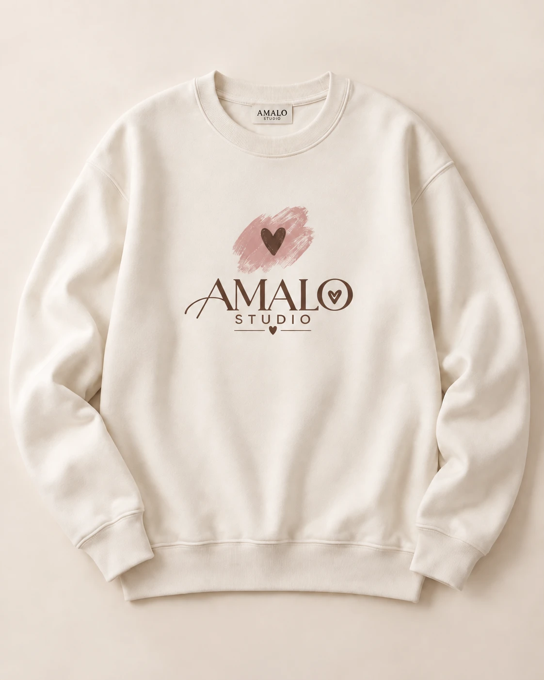 Buzo crema con estampado DTF del logo Amalo y corazón sobre pincelada rosa